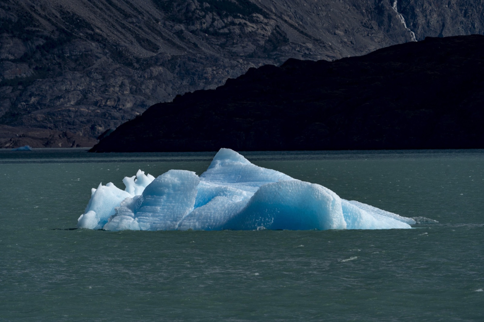 Blue iceberg lit against a dark valley wall